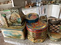 Overview of tea and biscuit tins arranged on countertop showing diverse shapes and colorful scenic illustrations