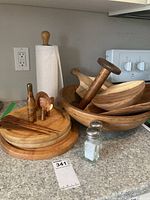 Group of wooden bowls, cutting boards, utensils, wooden elephant, paper towel holder, glass salt & pepper shakers on counter
