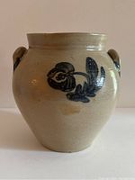 Front angle of the beige stoneware crock with a blue floral design, showing its shape and glaze texture.