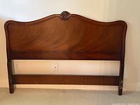 Front view of the walnut double bed headboard showing its size and shape against the wall.
