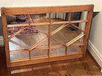 Mirror leaning against wall on hardwood floor, showcasing full front view