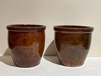 Front view of both brown glazed redware crocks side by side