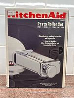 Front view of KitchenAid Pasta Roller Set box showing logo, product image, and features.