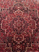 Close-up of central medallion showing red, navy blue and cream geometric motifs and knot detail