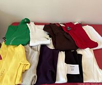 Grouped view of ten folded turtleneck sweaters in various colors displayed on a surface