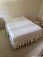 Queen mattress and box spring with skirt on carpeted floor