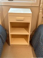 Front view of vintage white bedside table showing drawer and two open shelves.