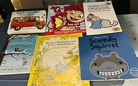 Books laid out on a flat surface showing titles: The Wheels on the Bus, G-Bugs Sam and the Singing Butterfly, Harold and the Purple Crayon, Heartwood Hotel, The Crayon the Elephant and the Very Small Elephant, Scaredy Squirrel at Night.