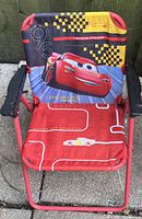 Single toddler folding lawn chair featuring Lightning McQueen from Cars, made of red metal frame and fabric seat with character graphics.