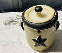 Ceramic candle warmer with lid, beige and black star design, with power cord visible