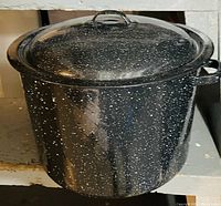Full view of the black speckled metal cooking pot with lid, showing the pot and lid together from front angle.