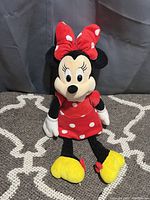 Minnie Mouse plush toy with red polka dot dress and bow, white gloves, yellow shoes with bows.
