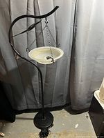 Full view of Serenity mist lamp suspended bowl hanging from curved black metal stand with base, remote on cord visible.