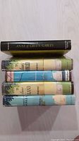 Spine view of five hardcover books from the Anne of Green Gables series stacked horizontally, showing titles and publisher markings indicating vintage library books.