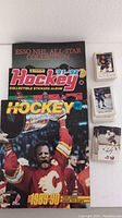 Three hockey sticker albums showing Esso NHL All-Star Collection, Panini 1991-92, and O-Pee-Chee 1989-90 with a photo of Calgary Flames player on cover
