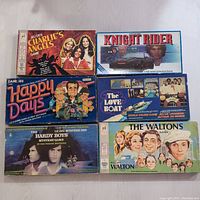 Six vintage TV show board games arranged in two rows, showcasing their original colorful boxes with title and artwork from shows Charlie's Angels, Knight Rider, Happy Days, The Love Boat, The Hardy Boys, and The Waltons.
