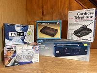 Photo showing all 5 electronic items in original boxes on wooden floor against wall.