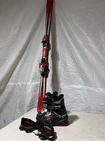 Full view of children’s skis upright with ski boots and goggles placed in front.