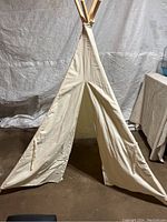 Front view of children's teepee tent showing open front door flap and fabric ties to secure doors.