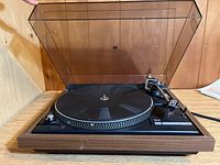 Front view of Dual 504 vinyl record player with clear dust cover open, showing wood base and platter.