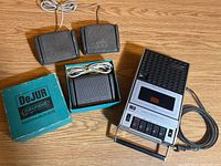 Three black Grundig footswitch pedals with one in original box and a Superscope portable cassette recorder with buttons and speaker grille shown on wooden floor