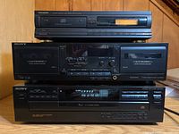 Three stacked audio units: GenExxa CD player on top, Sony TC-WR535 cassette player in middle, Sony CDP-C345 5-disc CD changer on bottom