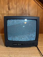 Front view of vintage Sylvania TV powered on displaying screen static.