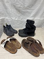 Four pairs of women's footwear including two Birkenstock sandals and two pairs of boots arranged on a flat surface, white background.