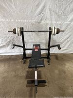 Front view of York Space Saver 230 folding workout bench with barbell on supports and multiple weights.