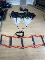 Photo showing the Wasp speed ladder fully extended on the floor with the SKLZ sprinting parachutes arranged above.
