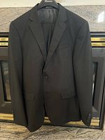Front view of navy blue men's suit jacket hanging on a Moores branded hanger showing the two button front and notch lapel collar.