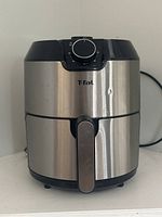 Image of T-fal air fryer showing front view with timer dial and handle, stainless steel body and black accents.