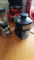 Osterizer blender on the left and the Cuisinart juicer on the right on a wooden surface.