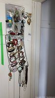 View of metal rack holding multiple costume jewelry bracelets and necklaces hanging vertically