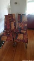 Two dining chairs with chrome legs and multicolor floral and geometric fabric upholstery, shown from the front angle.