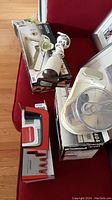 View of all items in lot including Kenmore food chopper, Oneida Mandolin slicer, and Zhenzhen sharpener on boxes