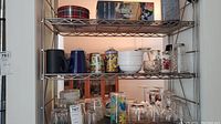 Shelving unit with multiple glassware and cups including coffee mugs, bowls, tumblers and glasses