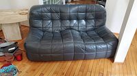 Front view of black leather loveseat showing tufted seat and back