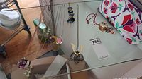 Several necklaces and pendants displayed on a glass table including a jewelry bag