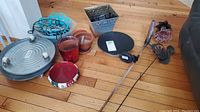 Full lot showing metal pot roller, various pots, square metal planter, and decorative items on wooden floor