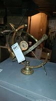 Brass armillary sundial with clear engraving and arrow gnomon, slight corrosion visible.