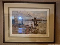 Framed print showing a man and dog in wetland with birds flying, dark wood frame and double matting