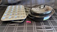Photos of a mini muffin pan with 24 cup molds, a 4-slot brownie pan, and a black speckled roaster with lid placed on a black checkered surface.