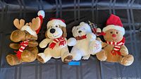 Front view of four Christmas-themed plush toys including a moose, dog, white bear, and gingerbread person, arranged in order with visible year embroidery.