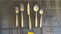 Closer view of one of each type of cutlery piece: salad fork, dinner fork, dinner knife, tablespoon, teaspoon showing the overall design and condition