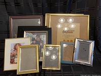 Group of 8 assorted picture frames on black fabric background showing various sizes, colors, and materials