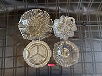 Top view of four glass serving dishes showing different shapes and patterns on black surface.