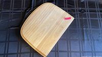 Wooden cutting board on dark fabric background, showing smooth surface and natural grain.
