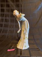 Front view of Royal Doulton porcelain figurine, showing young woman with flowing hair holding bouquet and wearing flowing dress with floral patterns.