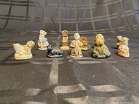 Group of 7 tea figurines including animals, children, and a grandfather clock